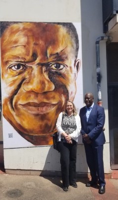 Le Dr. Mukwege et la Pr. Taxil devant le portrait du Dr. Mukwege réalisé par l'artiste AL1